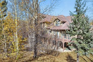 A two-story house with a balcony, surrounded by trees and a clear sky.