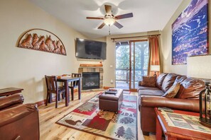 A living room with a fireplace, leather furniture, a flat-screen TV, and a large window with curtains. - Free SkyCard Activities - Gas Fireplace, Parking, Equipped Kitchen, Fitness Ctr (Breckenridge)