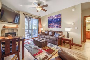 A living room with a fireplace, a television, a sofa, a coffee table, and a large window.