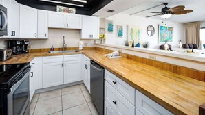 Een moderne keuken met witte kastjes, een houten aanrecht en een plafondventilator.