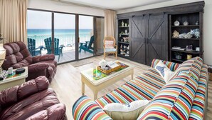 Een woonkamer met een bank, fauteuils, een salontafel en een boekenplank.