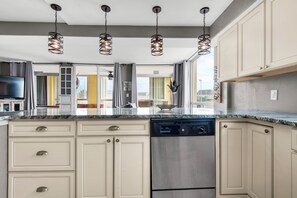 Prepare meals in the well-lit kitchen with a dishwasher and large windows offering a city view.