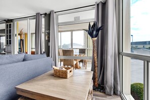 Relax in a spacious room with a large window offering views of the surrounding area, a comfortable sofa, and a decorative vase.
