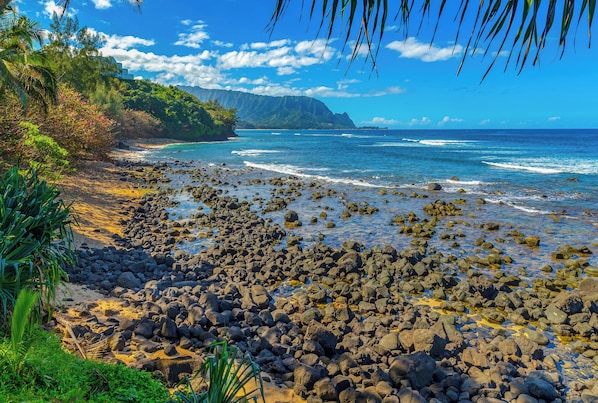 Una spiaggia rocciosa con acque cristalline e montagne sullo sfondo.