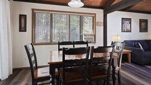 Un coin repas avec une table et des chaises en bois, une fenêtre avec des stores et un ventilateur de plafond.