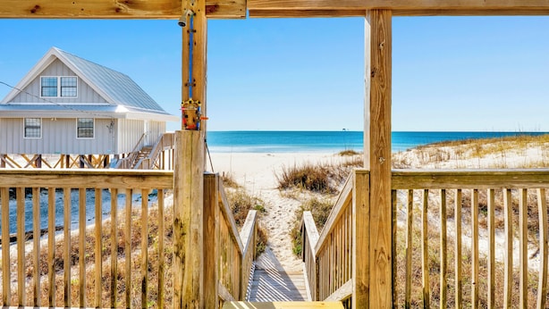 A wooden deck leading to a beach with a house in the background. - Gulf Front | Pet Friendly | Shared Pool (Gulf Shores)