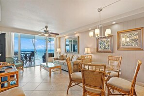 A spacious living room with a balcony, wicker furniture, and a large window offering a view.