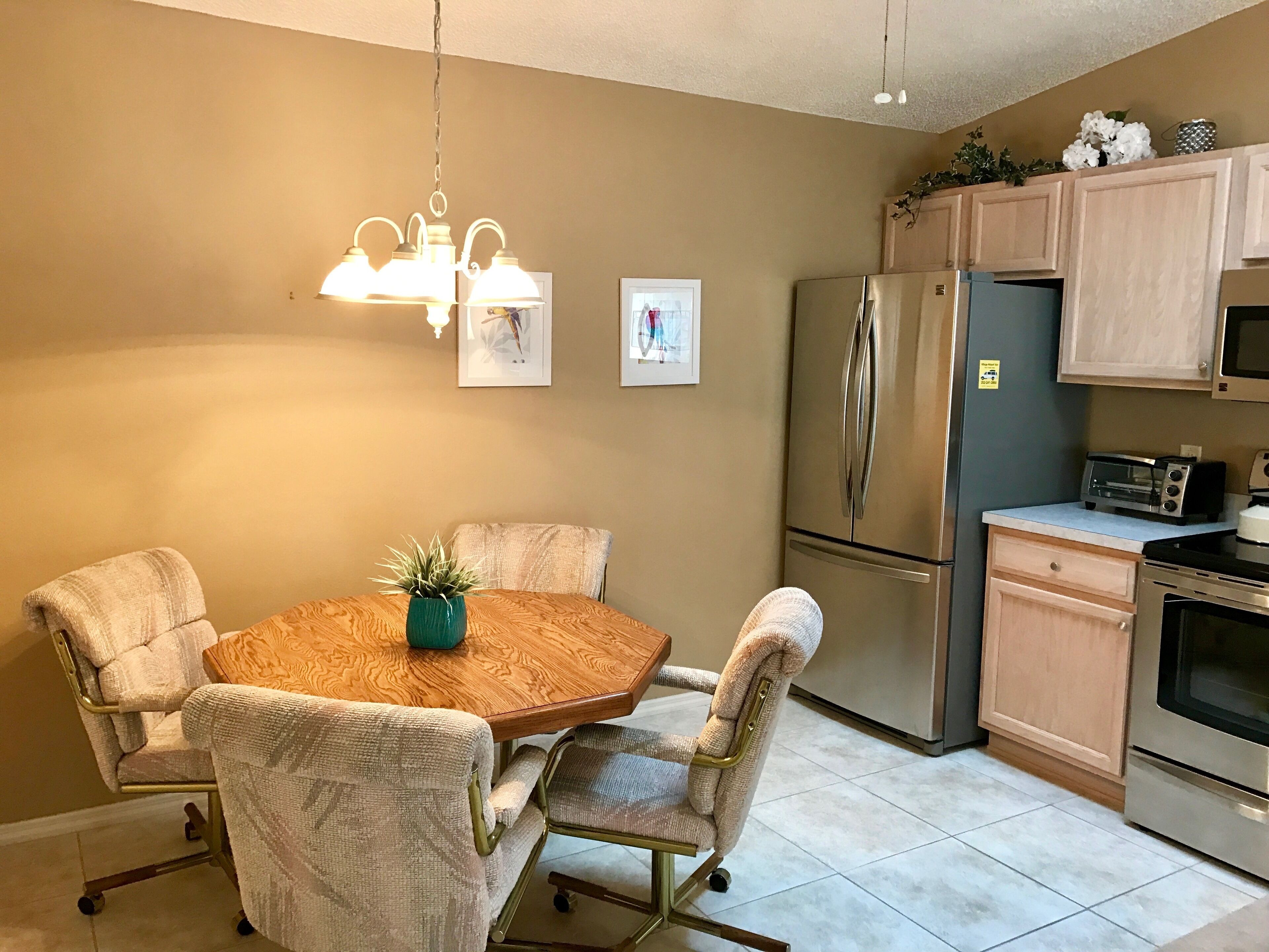A compact kitchen with a dining table, chairs, a refrigerator, a microwave, and a toaster.