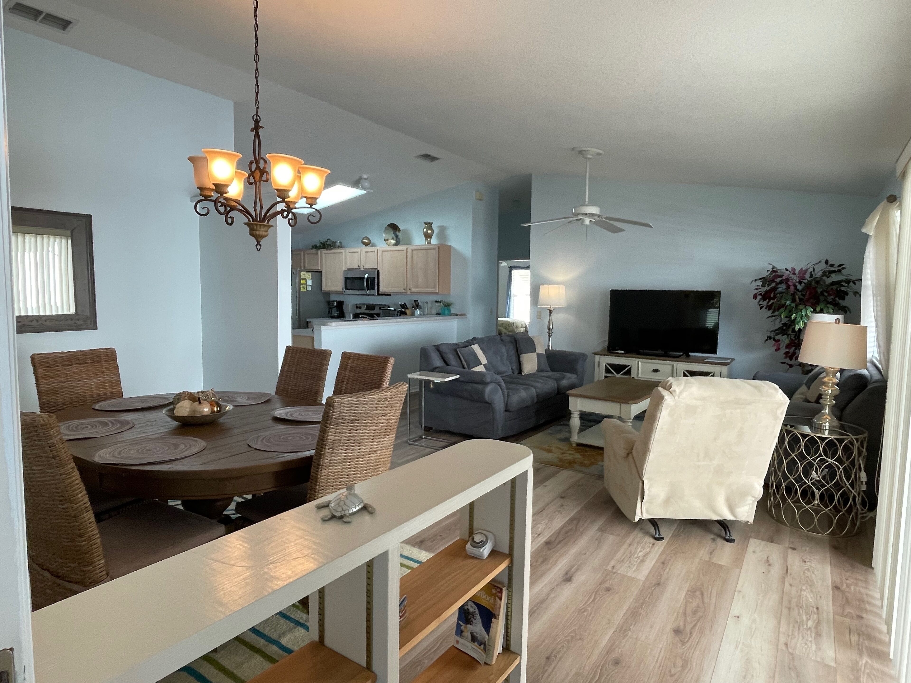 A spacious living area with a dining table, sofas, and a TV.