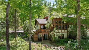 Eine zweistöckige Lodge mit Balkon, umgeben von Wald.