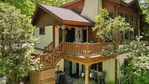 Eine Holzhütte mit einem Balkon, einer überdachten Terrasse und einer Terrassenfläche mit Sitzgelegenheiten im Freien.