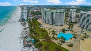 Un hotel costero con varios edificios altos, una playa y una piscina.