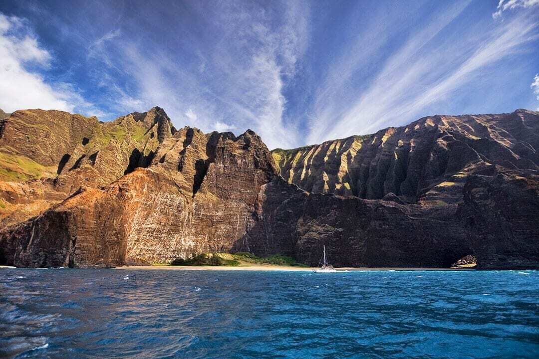 A coastal landscape with rocky cliffs and a clear blue sea.