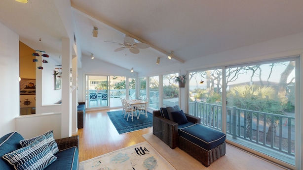 Ein großzügiger Wohnbereich mit einer großen Schiebeglasdoor zum Terrassenausgang, einem Deckenventilator und einem Essbereich mit Tisch und Stühlen.