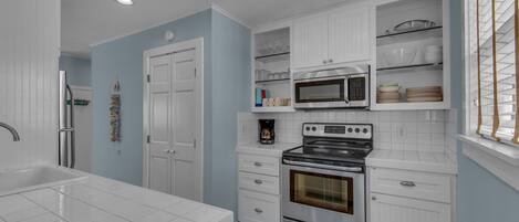A modern kitchen with white cabinetry, a stainless steel refrigerator, a built-in oven, and a microwave.