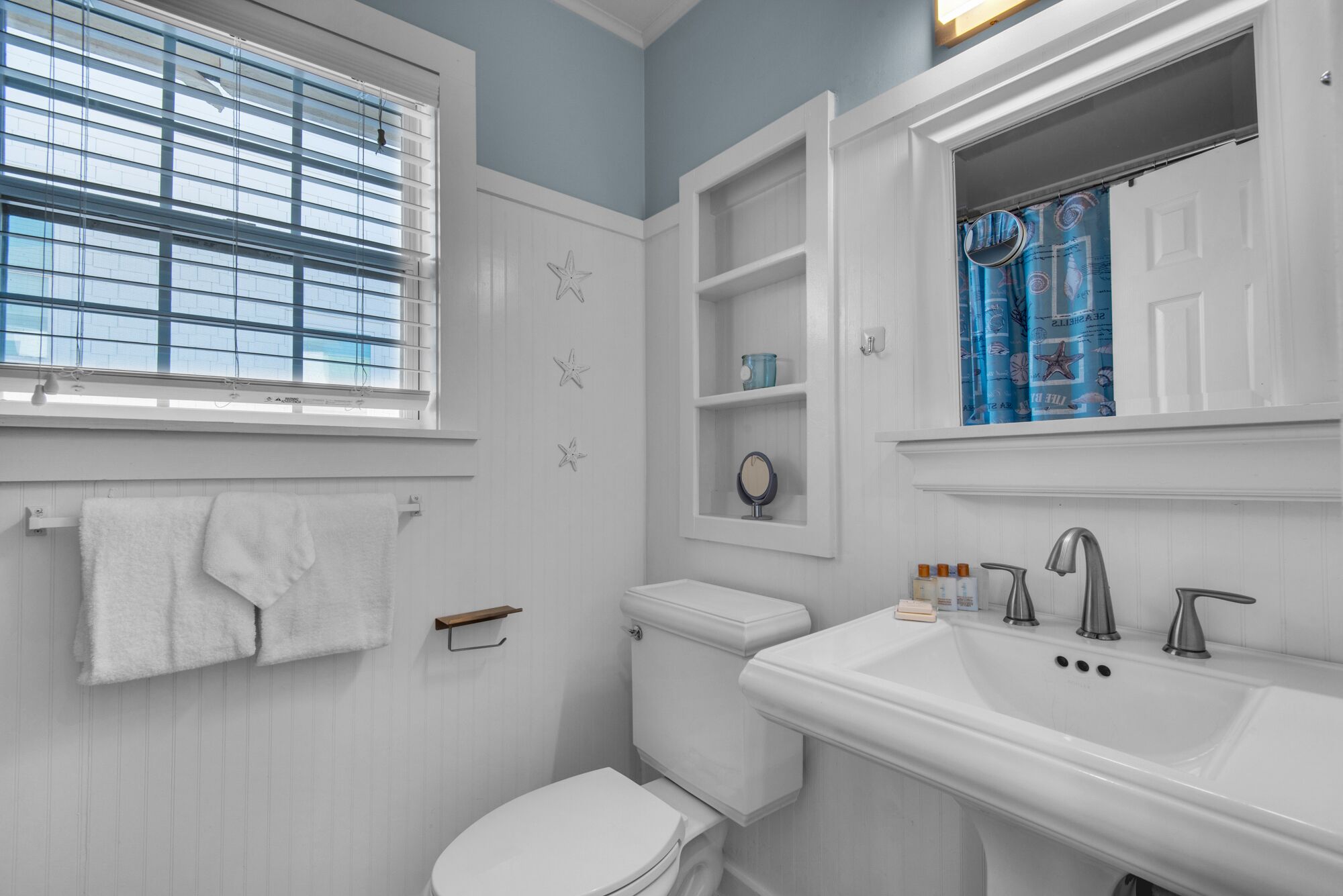 Une salle de bain avec des toilettes, un lavabo et une fenêtre.