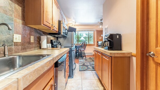 A kitchen with wooden cabinets, a stainless steel sink, and a tiled backsplash. - Top Floor Unit with Many Upgrades! Ski In, Walk Everywhere! | PM6A (Breckenridge)