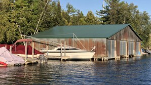 Ein Steg mit einem Boot und einer Hütte am Wasser.