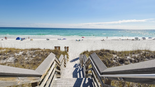 A beach with a wooden boardwalk leading to the water, sandy beach, and tents. - Cozy 1 Bedroom🏝️ Gulf Views🌊Summerspell 309 (Miramar Beach)