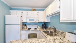 A kitchen with white cabinets, a microwave, a stove, a sink, and a toaster. - Cozy 1 Bedroom🏝️ Gulf Views🌊Summerspell 309 (Miramar Beach)