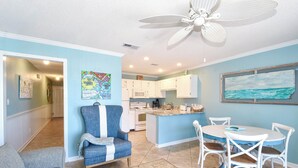 A living room with a blue sofa, a blue armchair, a wooden coffee table, and a dining area with a white table and chairs. - Cozy 1 Bedroom🏝️ Gulf Views🌊Summerspell 309 (Miramar Beach)