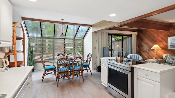 A compact kitchen with a dining area, wooden beams, and a large window. - Beachwalk 174 - Shipyard 3BR/3.5 BA Townhouse (Hilton Head Island)
