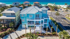 Un immeuble à plusieurs étages doté de balcons, situé près d’une plage aux eaux d’un bleu limpide.