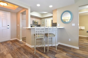 A kitchen with a microwave, stove, and bar stools.