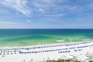 A beach with rows of blue umbrellas and white sand.