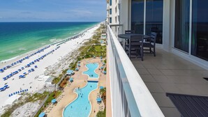 Varanda de hotel com vista para uma praia e área de piscina.