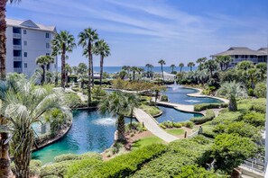A resort with multiple swimming pools, palm trees, and a view of the ocean.