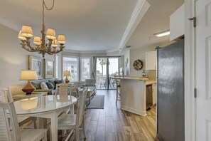 Une cuisine moderne avec un coin repas, un lustre et une vue à travers la porte vitrée.