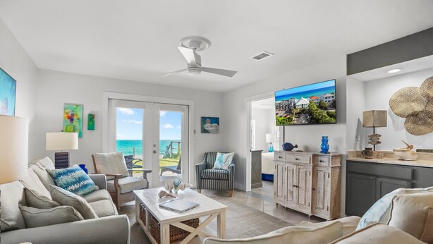 A modern living room with a sofa, armchair, coffee table, and a television. - "Sunseekers 2" | Beachfront | Ground Floor with Open Greenspace, and Amazing Views (Santa Rosa Beach)