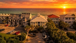 A coastal hotel with multiple-story buildings, a parking lot, and a view of the ocean at sunset. - "Sunseekers 2" | Beachfront | Ground Floor with Open Greenspace, and Amazing Views (Santa Rosa Beach)