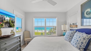 A bedroom with a large bed, a ceiling fan, a window with a view of the beach, a dresser, and a chair. - "Sunseekers 2" | Beachfront | Ground Floor with Open Greenspace, and Amazing Views (Santa Rosa Beach)