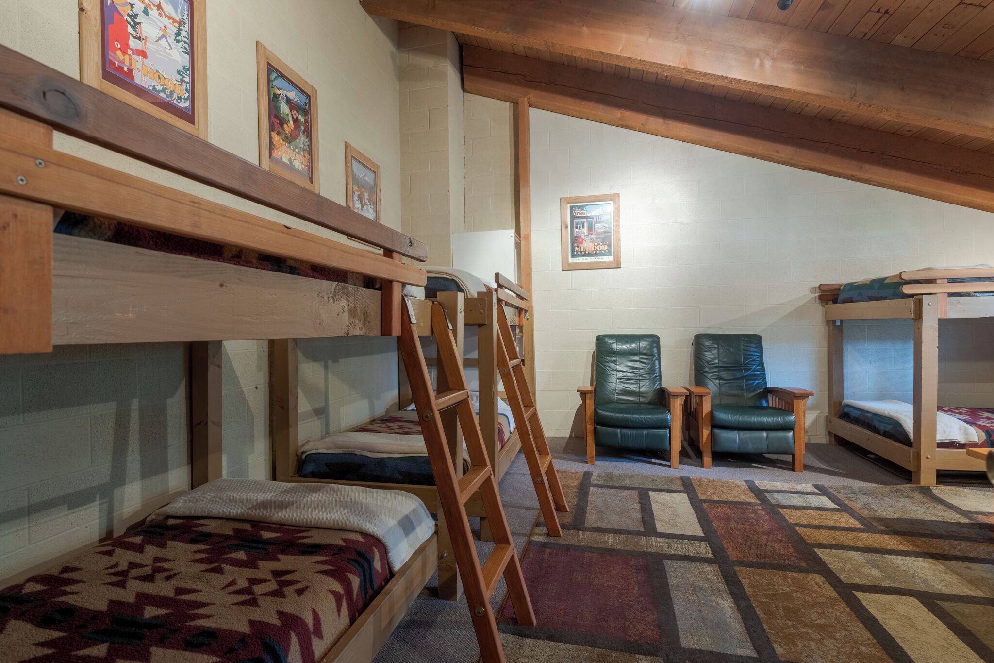 Une chambre de dortoir avec des lits superposés, une échelle, une chaise et une petite table.