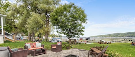 An outdoor patio with wicker furniture, a fire pit, and a view of the water.