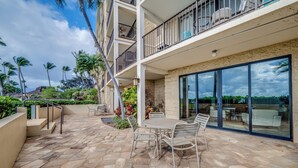 A multi-story building with a patio area featuring a stone floor, outdoor furniture, and a view of the surrounding landscape.