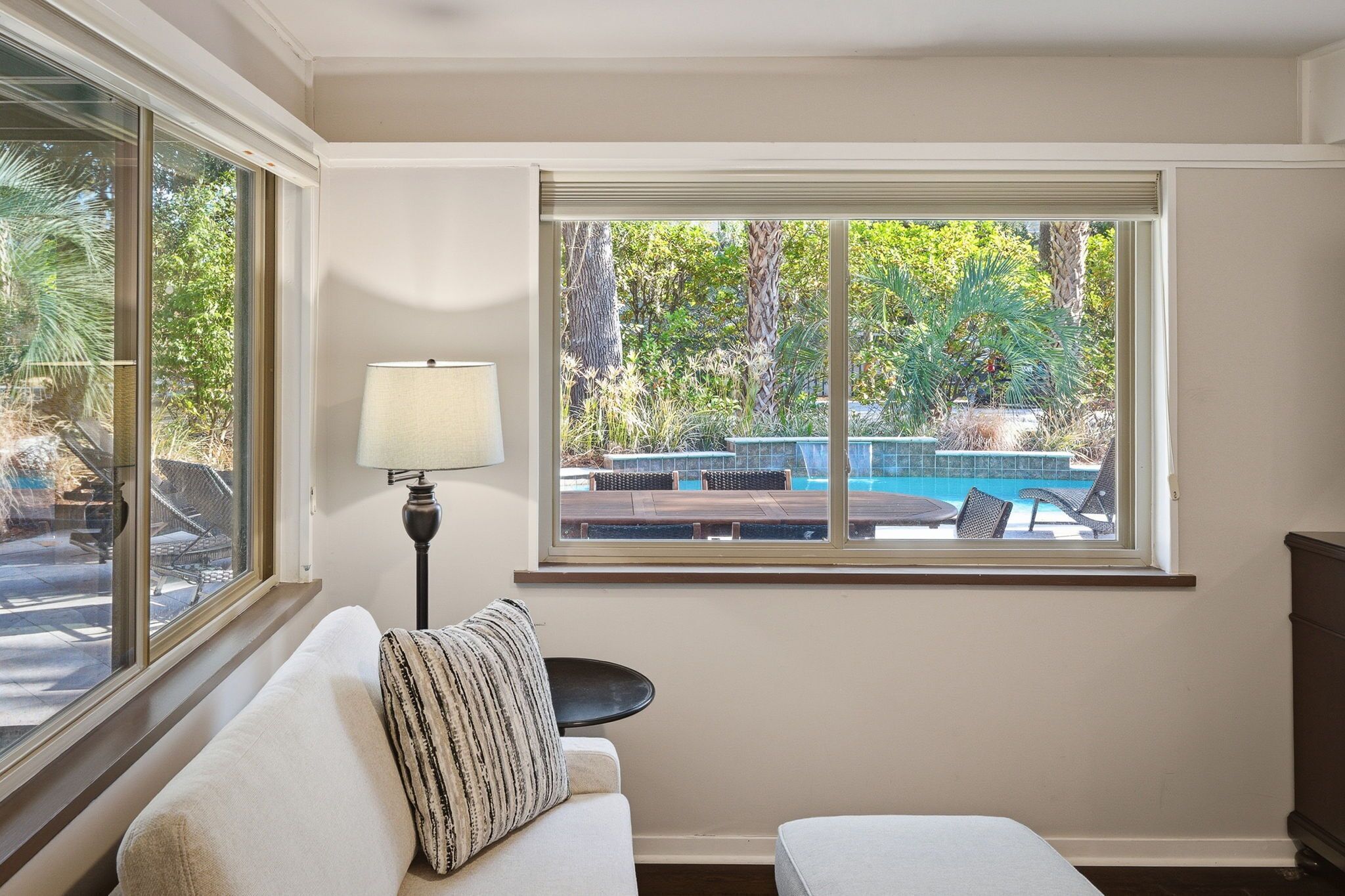 A room with a large window overlooking a pool and greenery.