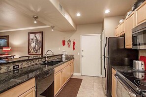 Eine Küche mit Granit Arbeitsplatten, einem Kühlschrank, einer Mikrowelle und Holzschränken.