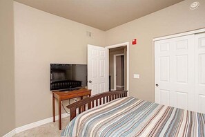 Una camera da letto con un letto, una TV su un mobile, una porta e un corridoio.