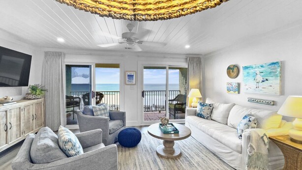 A spacious living room with a large TV, comfortable seating, a coffee table, and a balcony with a view of the sea. - "Endless Waves-208" | Beachfront | Stunning Beach Views | Bike to Seaside (Seagrove Beach)