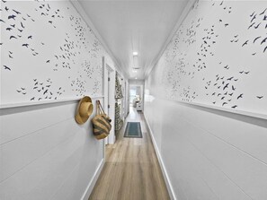 Stylish hallway with a unique bird silhouette pattern and woven bags, leading to a cozy room.
