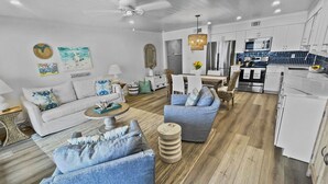 A modern living room with a sofa, coffee table, and a dining area with chairs. - "Endless Waves-208" | Beachfront | Stunning Beach Views | Bike to Seaside (Seagrove Beach)