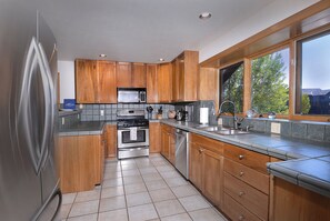 Una cocina con armarios de madera, un refrigerador de acero inoxidable, un microondas, una estufa y un lavaplatos.