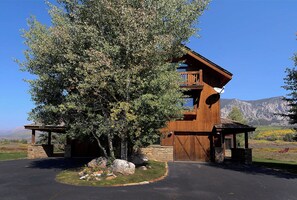 Eine Holzhütte mit Steinunterbau, einer Veranda und einem Berg im Hintergrund.