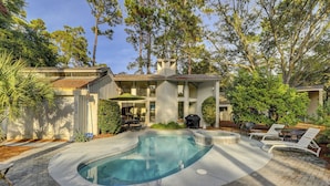 Ein Haus mit Swimmingpool, Gartenmöbeln und einer Grillgelegenheit.