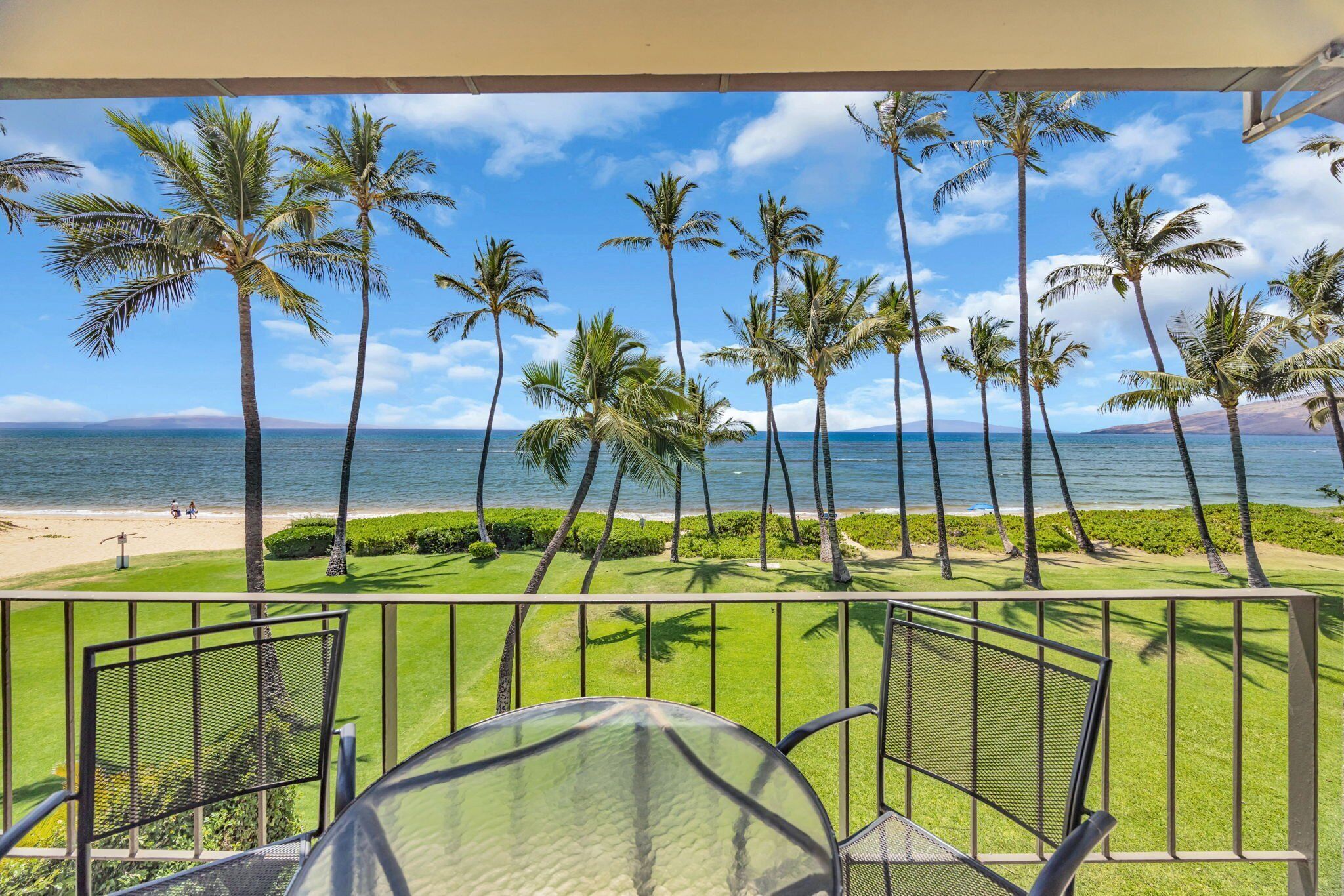 A balcony with a view of the beach and palm trees.