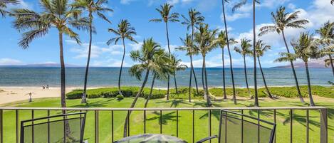 A balcony with a view of the beach and palm trees.