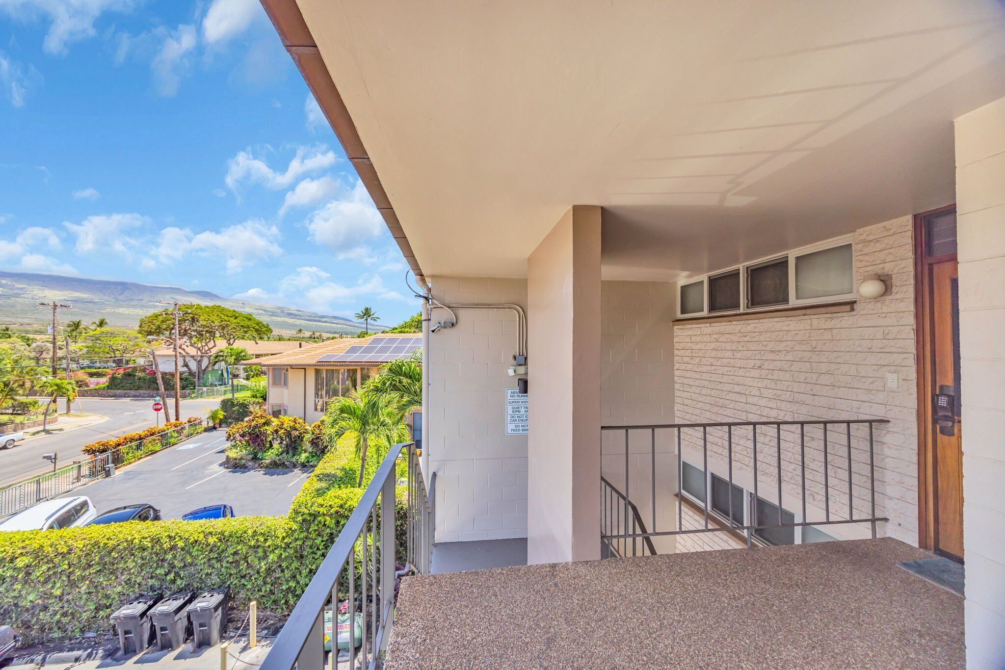A balcony with a view of a street and mountains.